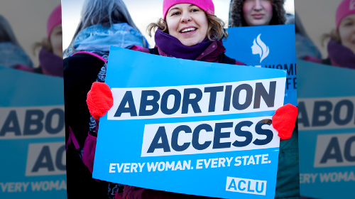 Woman holding abortion access sign at a rally