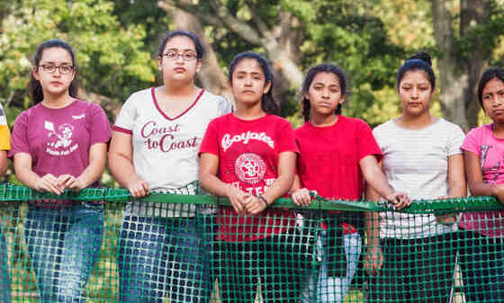 Immigrant girls and women standing at a fence