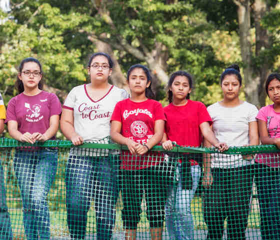 Immigrant girls and women standing at a fence