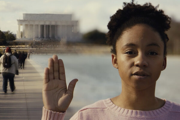 Little girl raising her right hand in front of Lincoln Memorial