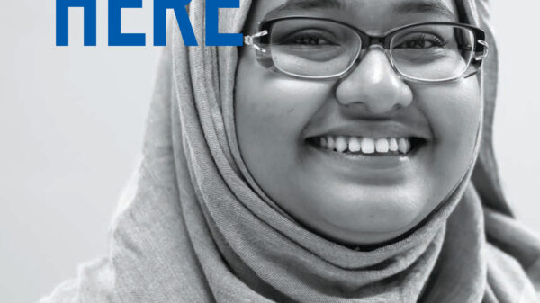 We Belong Here report cover with picture of smiling girl in hijab and glasses