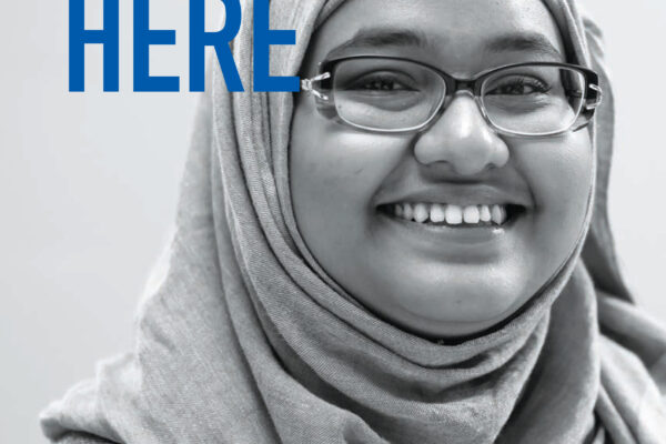 We Belong Here report cover with picture of smiling girl in hijab and glasses