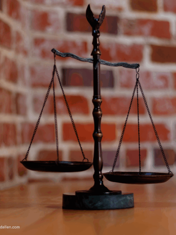 balanced scales of justice in front of brick wall