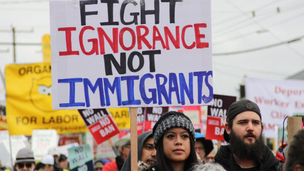 A protester holding a sign with the text "fight ignorance not immigrants"