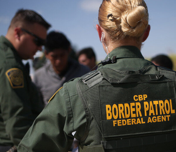 View of CBP agent from the back with green uniform and marking reading "CBP / Border Patrol / Federal Agent"