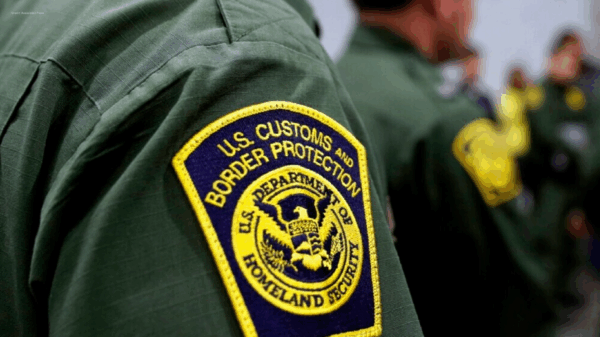 Yellow and blue CBP badge on green shirt