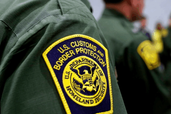 Yellow and blue CBP badge on green shirt