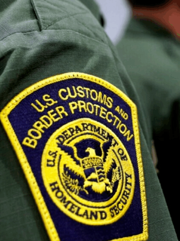 Yellow and blue CBP badge on green shirt