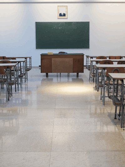 Empty classroom with green chalkboard on wall at end