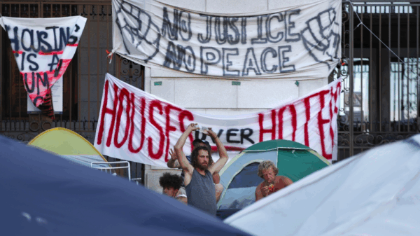 Banners hanging on Portland City Hall reading "No justice no peace" and "houses over hotels"