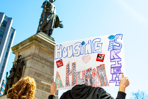 Person holding poster reading "housing is a human right."