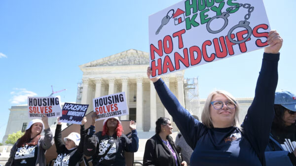 Person holding poster reading "house keys not handcuffs" in front of Supreme Court building