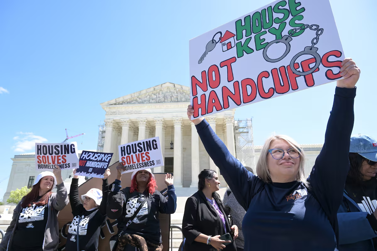 Person holding poster reading "house keys not handcuffs" in front of Supreme Court building
