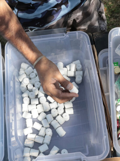 A hand taking harm reduction supplies for addicts from the middle of 3 bins.