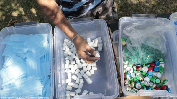 A hand taking harm reduction supplies for addicts from the middle of 3 bins.