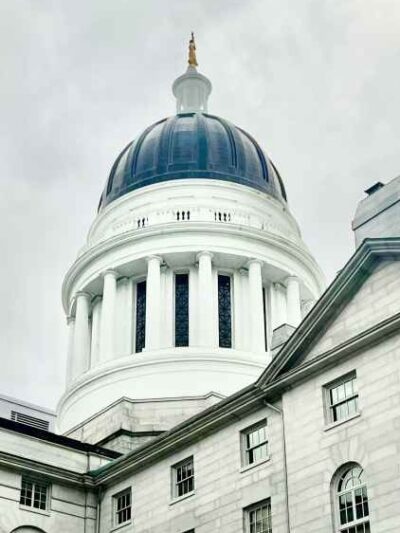 Rotunda of Maine Statehouse with cloudy skies behind