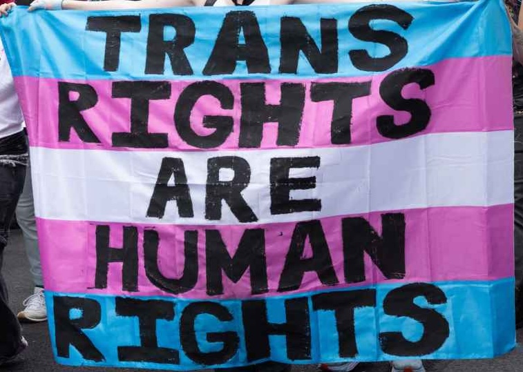 Trans Rights, speakers, protesters, and supporters denounce the Trump Administration's persistent attacks on the transgender community. by carrying a huge sign reading" TRANS RIGHTS ARE HUMAN RIGHTS".