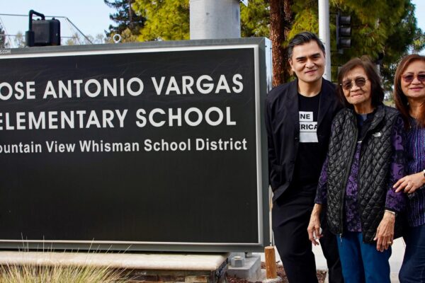 A smiling Jose Antonio Vargas and two equally joyful female family members stand to the right of a large sign that reads "JOSE ANTONIO VARGAS