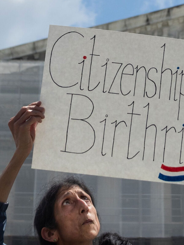 A demonstrator looks up at her sign (which reads "Citizenship is a Birthright") during a rally outside the Supreme court building demanding the court uphold the 14th Amendment to the U.S. Constitution.
