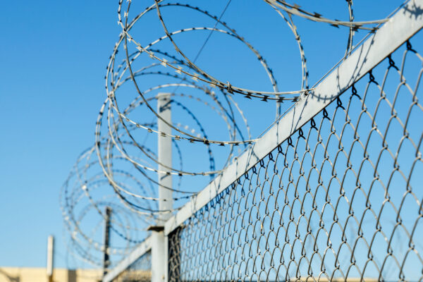 A chain link fence with razor wire running along the top.