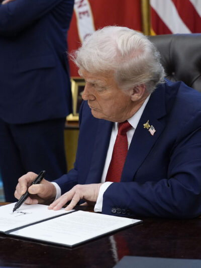 President Trump signs an executive order in the Oval Office of the White House.