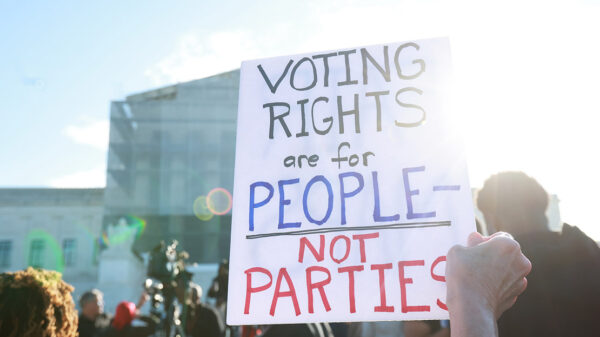 An individuals holding a sign saying "Voting Rights Are For People Not Parties," outside of the U.S. Supreme Court ahead of arguments in the Voting Rights case Callais v. Landry.