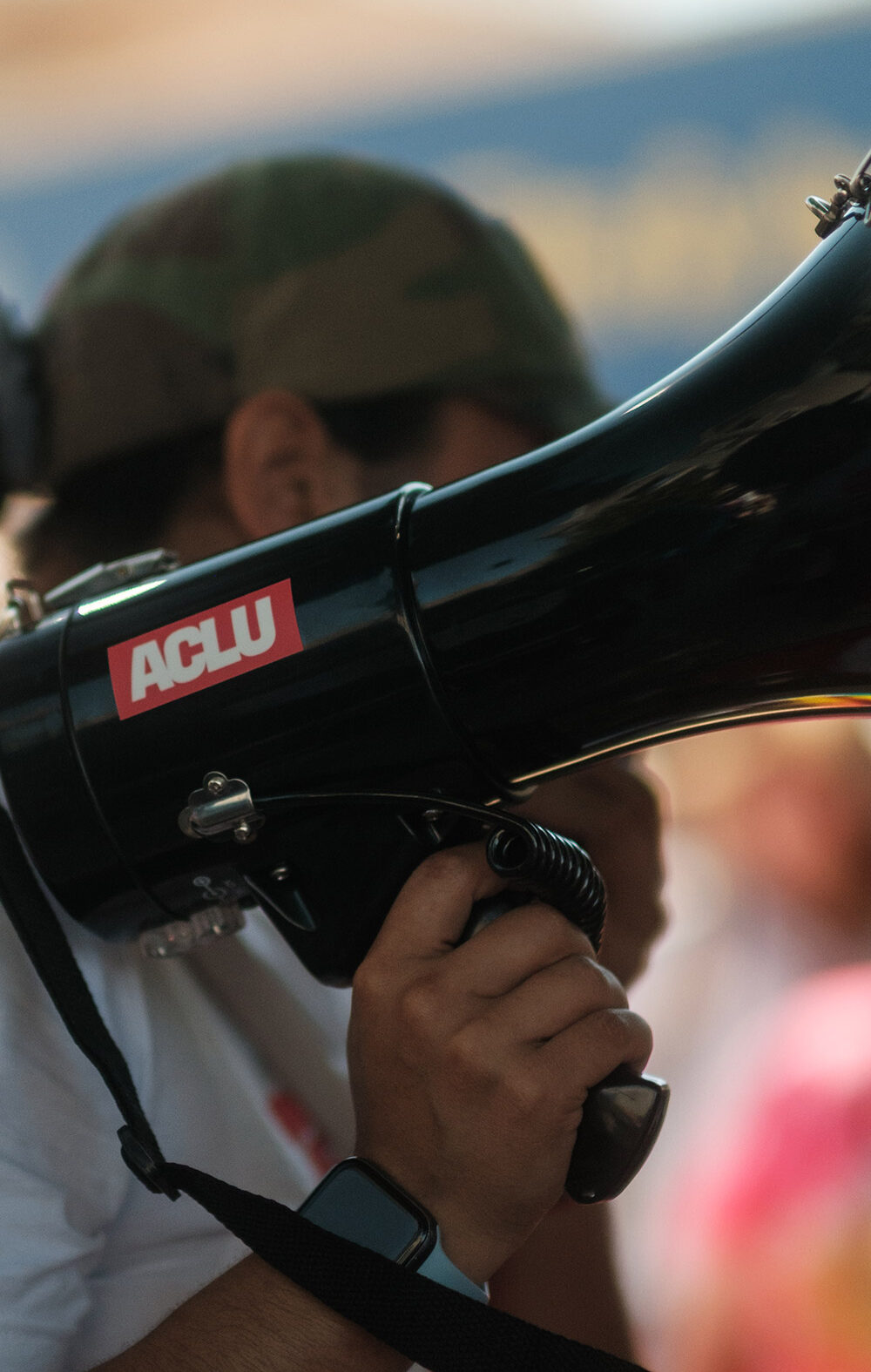A demonstrator holding a megaphone with an ACLU sticker.
