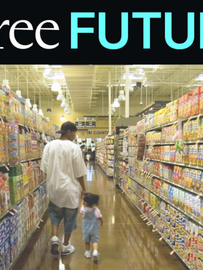 A man holding a child's hand and walking down a colorful grocery store aisle