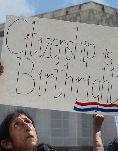 woman holding "citizenship is a birthright" sign