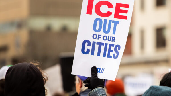 Person holding poster at protest reading: ICE OUT OF OUR CITIES