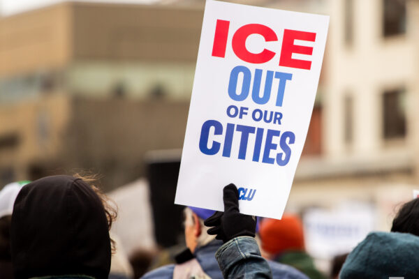 Person holding poster at protest reading: ICE OUT OF OUR CITIES