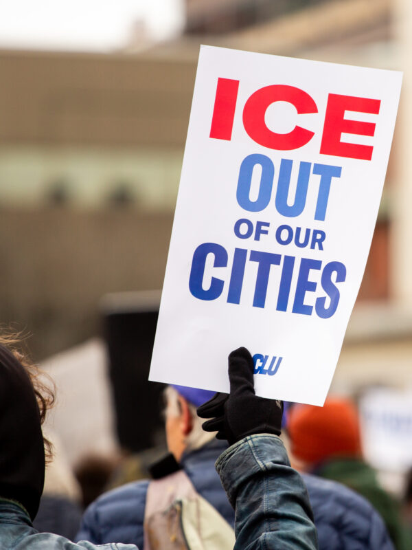 Person holding poster at protest reading: ICE OUT OF OUR CITIES