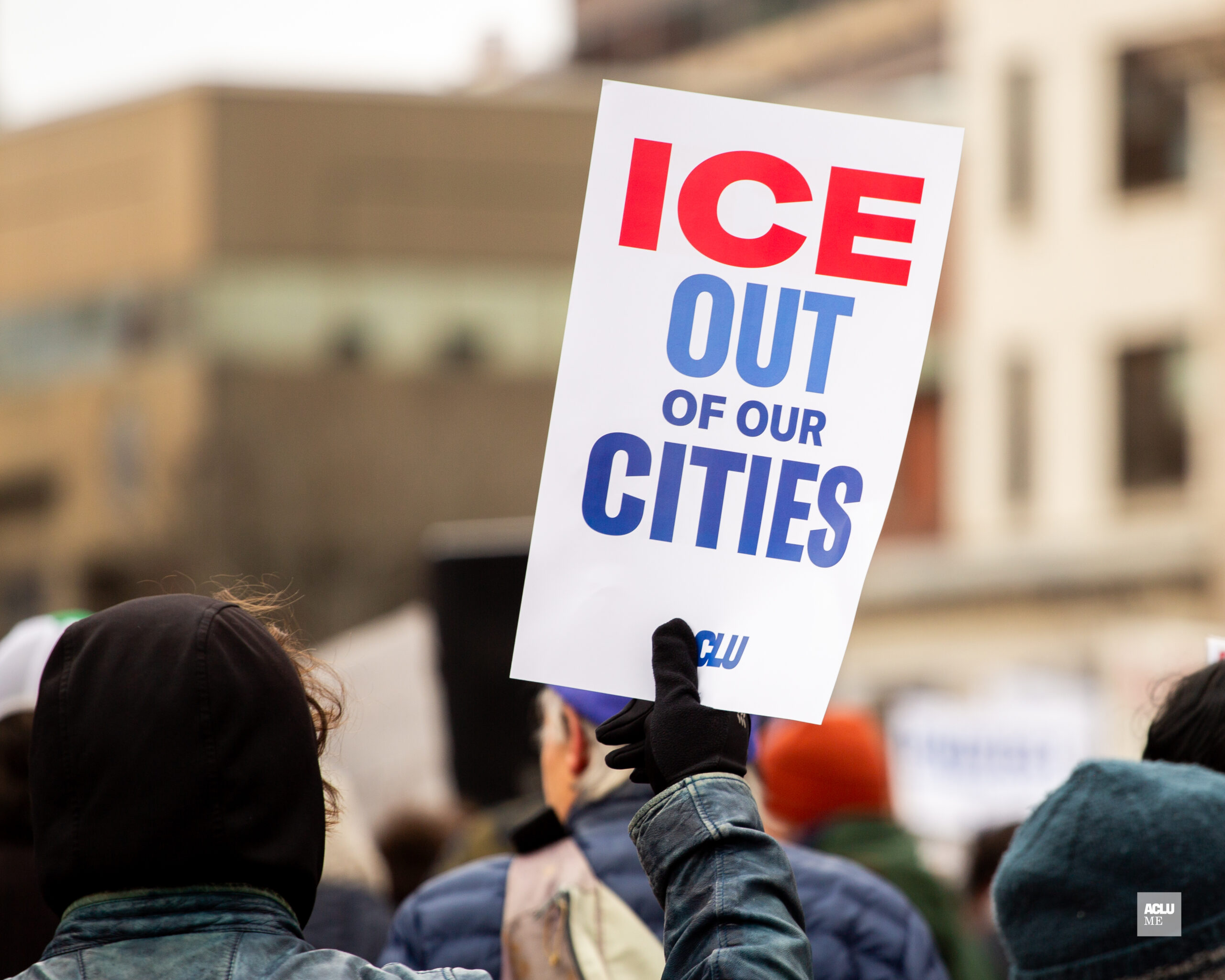 Person holding sign at protest reading: ICE OUT OF OUR CITIES