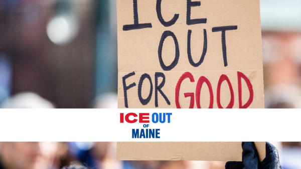 Person holding homemade protest sign reading: ICE OUT FOR GOOD