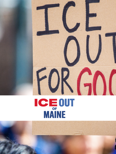 Person holding homemade protest sign reading: ICE OUT FOR GOOD.