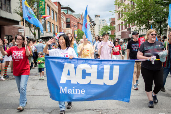 People walking in parade carrying a blue ACLU of Maine banner.