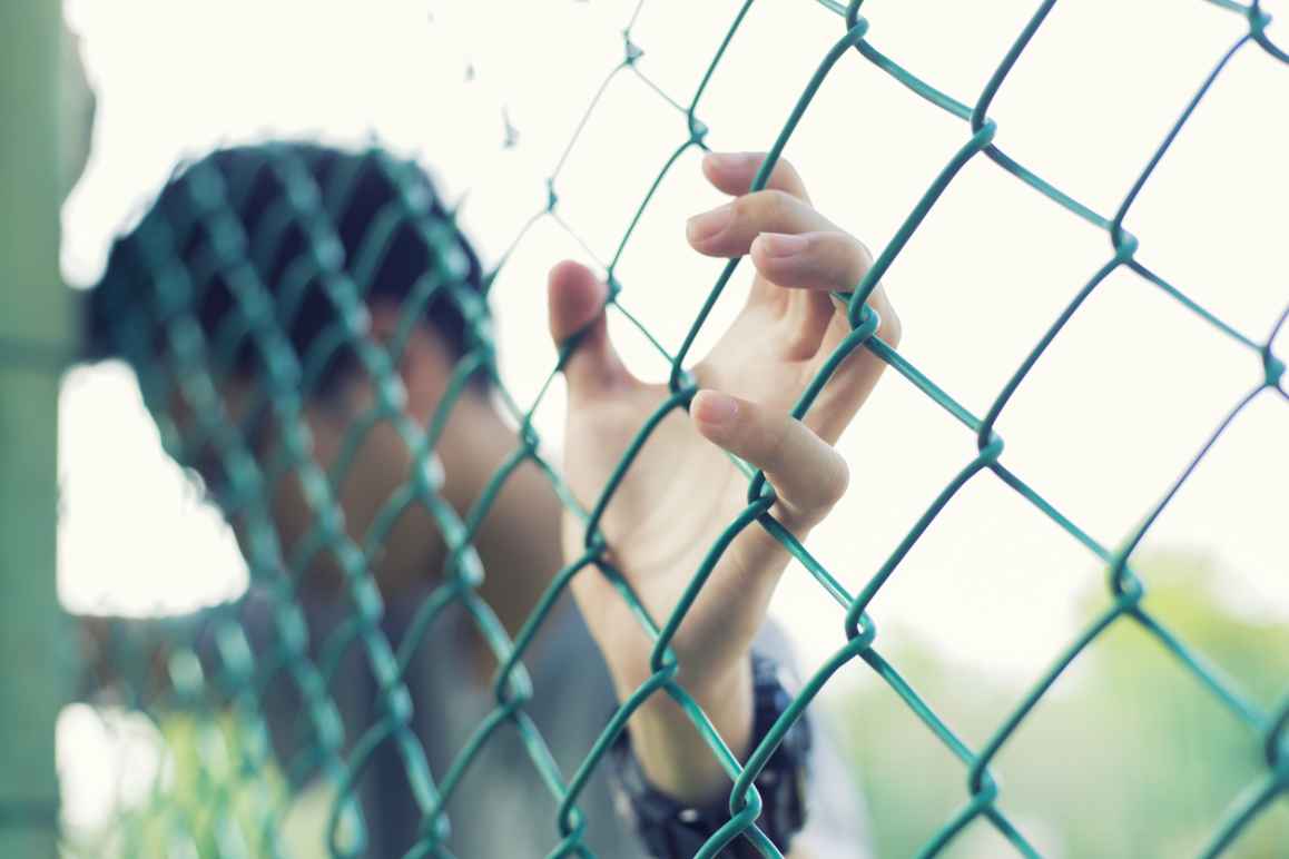 Child leaning on chainlink fence