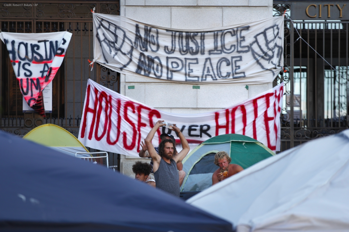 Banners hanging on Portland City Hall reading "No justice no peace" and "houses over hotels"