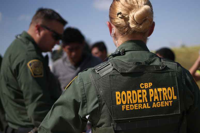View of CBP agent from the back with green uniform and marking reading "CBP / Border Patrol / Federal Agent"