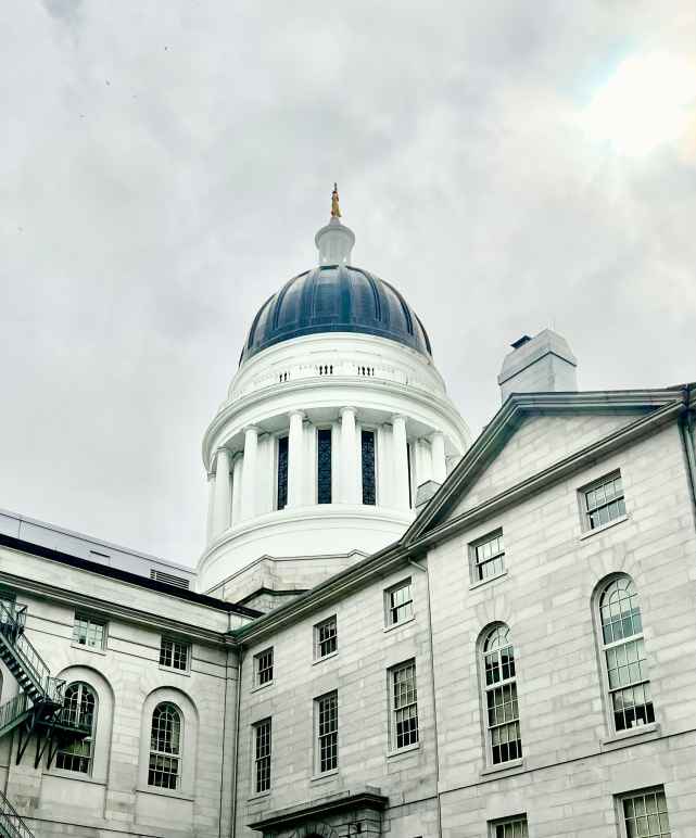 Rotunda of Maine Statehouse with cloudy skies behind