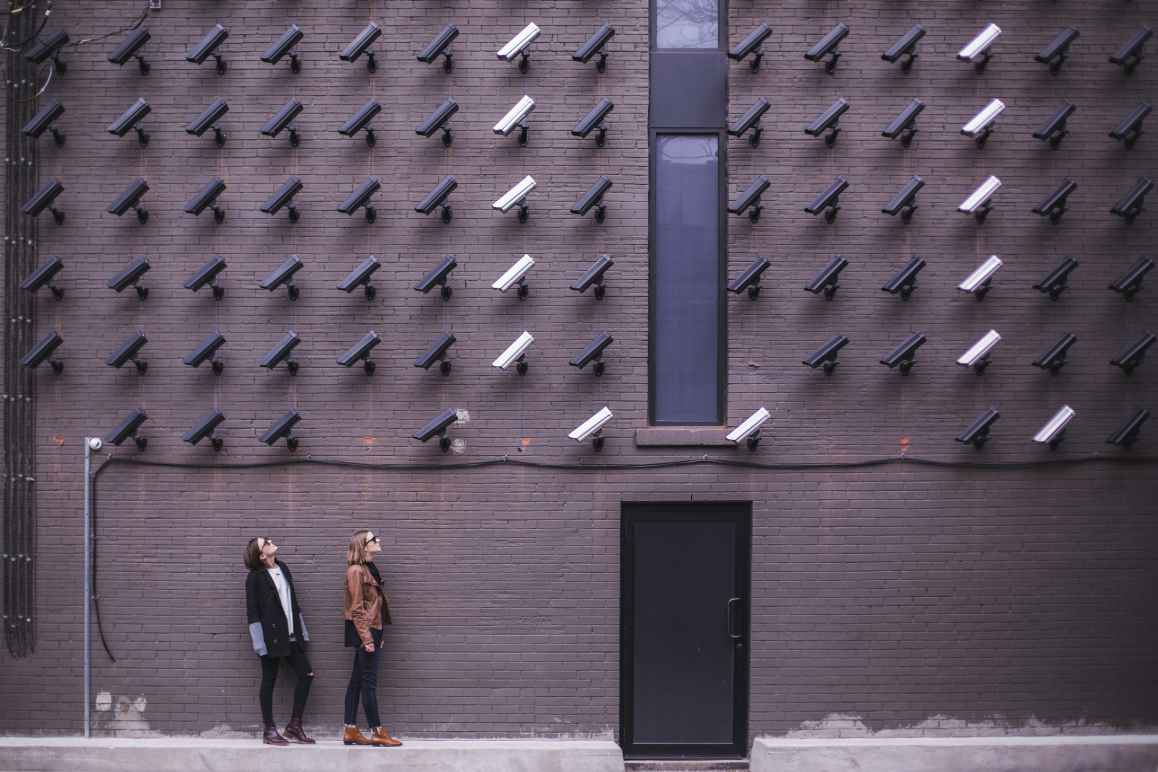 Two women looking up at a wall covered in security cameras