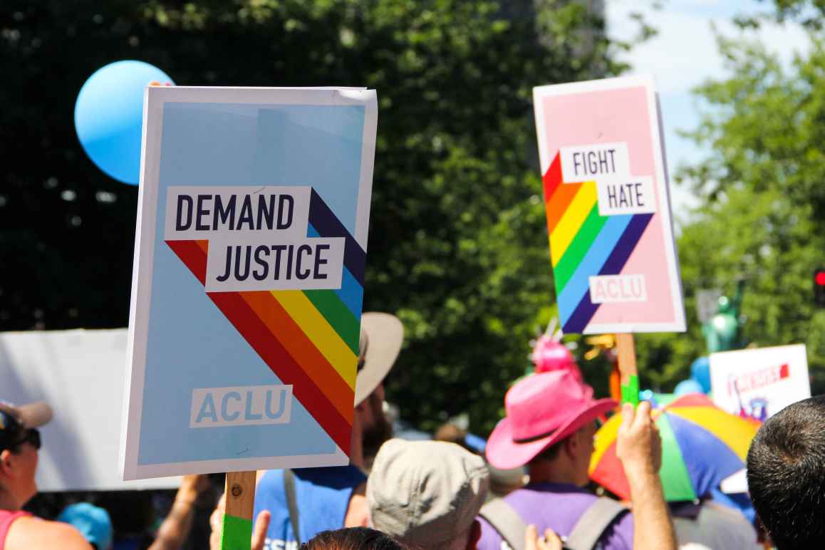 People marching for Pride. One visible signs reads "Demand Justice"