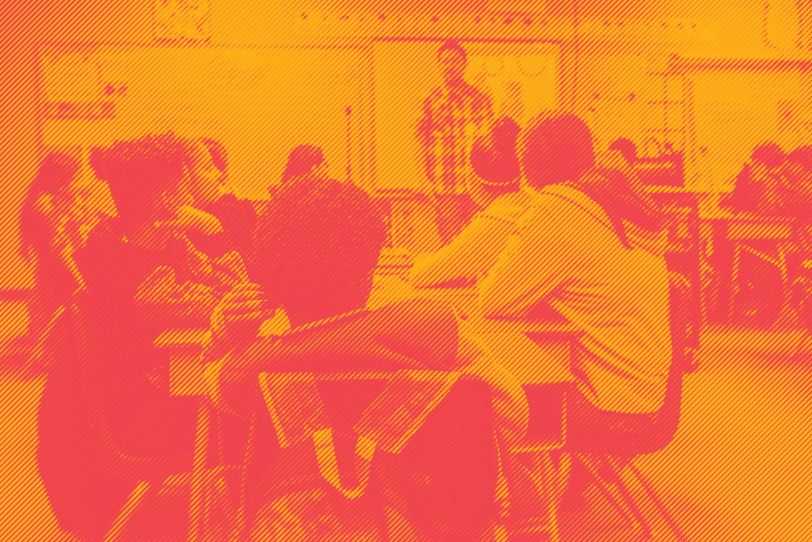 Students sitting at desks in classroom with teacher in front of class. Photo is in an orange and red duotone effect.