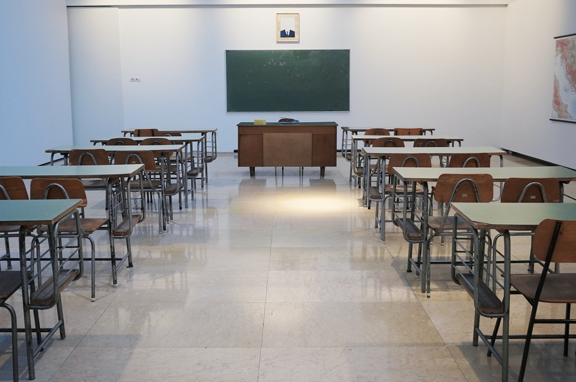 Empty classroom with green chalkboard on wall at end