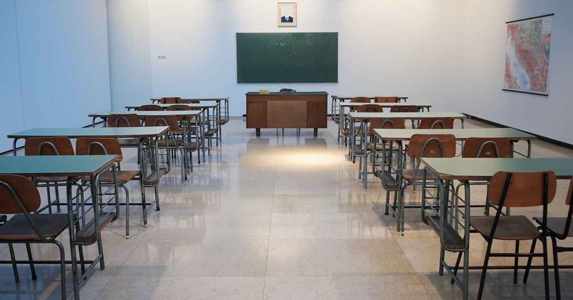 Classroom with desks and green chalkboard on wall.