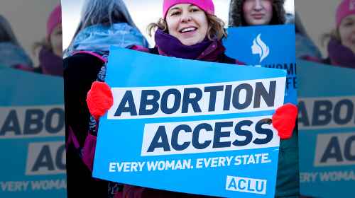 Woman holding abortion access sign at a rally