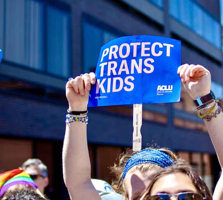 Protect Trans Kids Placard at 2024 Portland Pride Parade Person holding blue poster reading "protect trans kids" while marching in Portland Pride Parade, 2024.