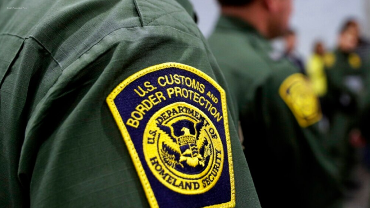 Yellow and blue CBP badge on green shirt