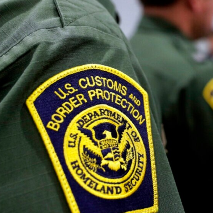 Yellow and blue CBP badge on green shirt