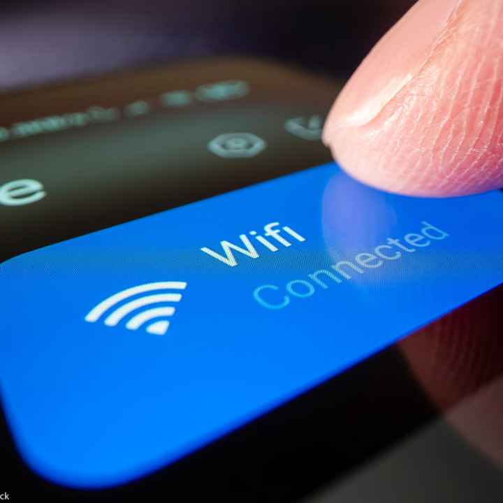 A finger touching a phonescreen to connect to wifi.